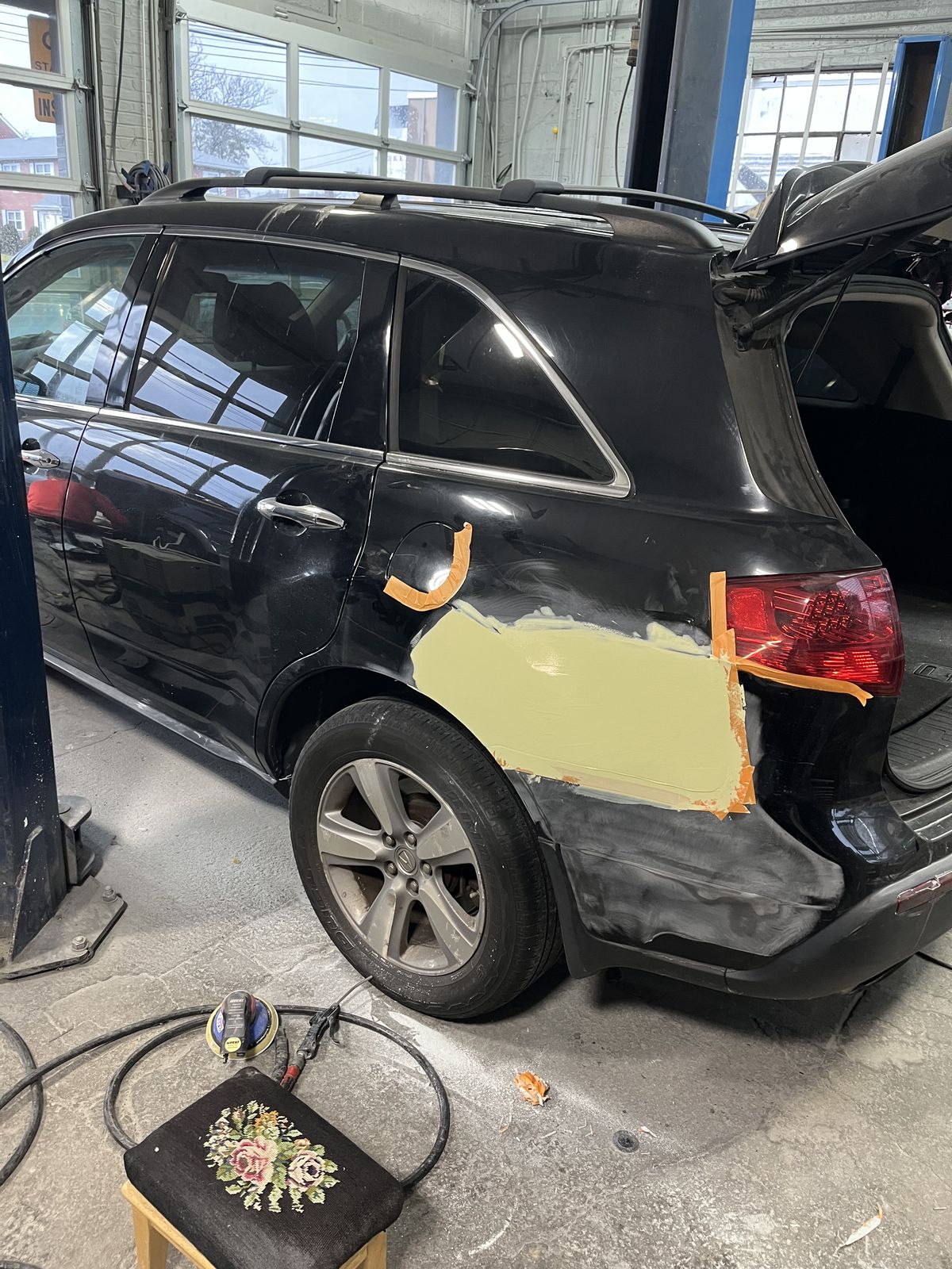 Body filler being shaped on a rear quarter panel