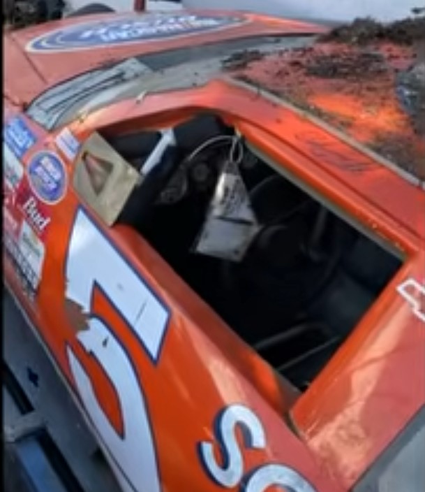 Orange Schneider-branded Chevrolet race car with weathered paint and sponsor decals before restoration