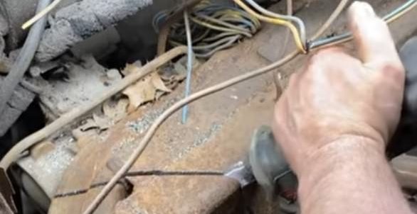 Worker cutting a marked section of rusty metal under the hood of the world’s longest limo