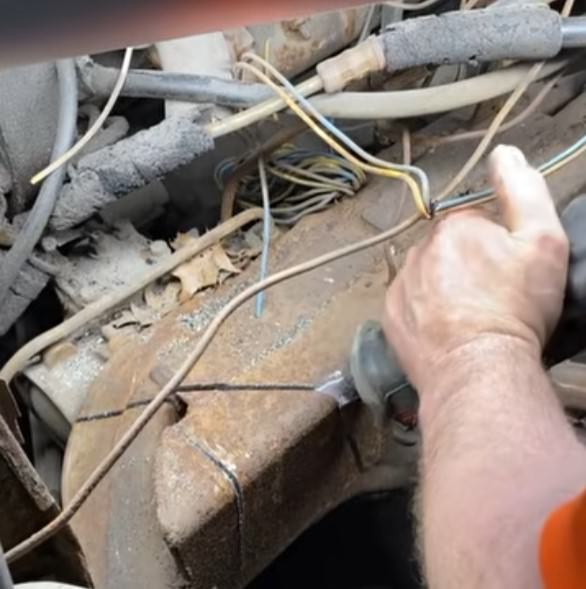Worker cutting a marked section of rusty metal under the hood of the world’s longest limo